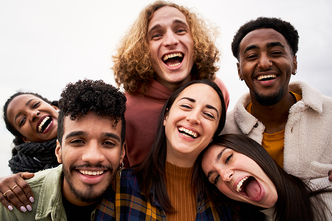 Selfie of Group of young cheerful people looking at the camera outdoors. Happy smiling friends hugging. Concept of community and youth lifestyle. High quality photo